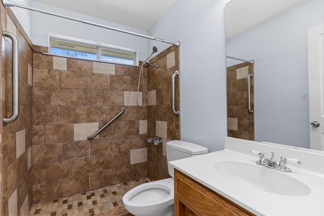 bathroom featuring a tile shower, vanity, and toilet