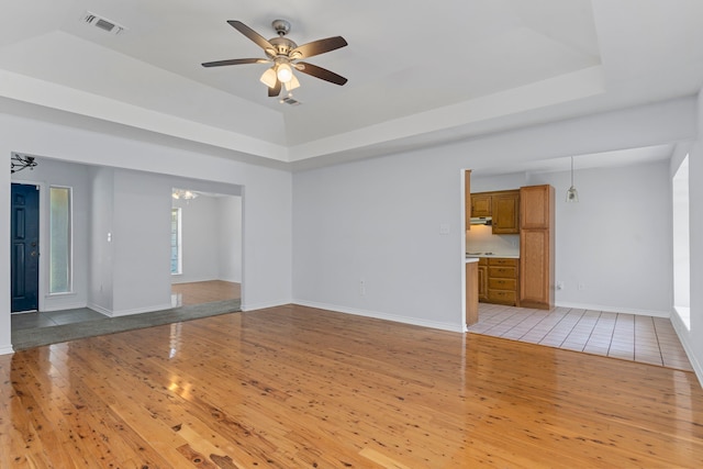 empty room featuring ceiling fan with notable chandelier and light hardwood / wood-style floors