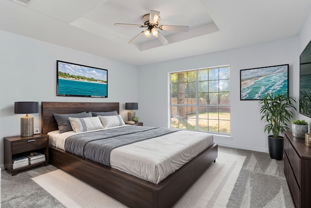 carpeted bedroom featuring a tray ceiling and ceiling fan