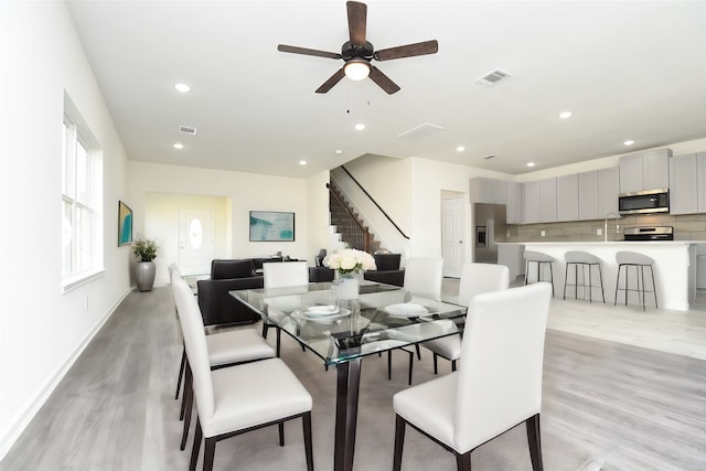 dining room with ceiling fan, sink, and light hardwood / wood-style floors