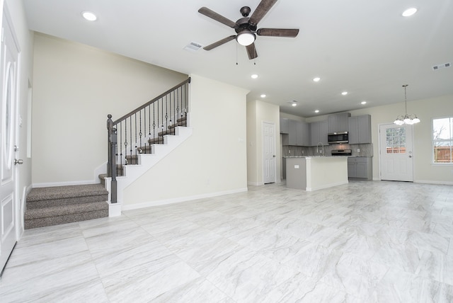 unfurnished living room with ceiling fan with notable chandelier and sink