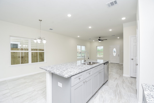 kitchen featuring an island with sink, sink, decorative light fixtures, dishwasher, and light stone countertops