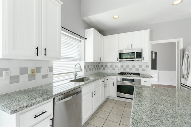 kitchen featuring white cabinets, sink, light tile patterned floors, light stone counters, and stainless steel appliances