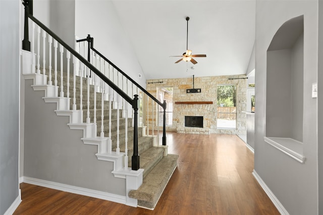 entrance foyer with ceiling fan, a fireplace, a towering ceiling, and hardwood / wood-style flooring