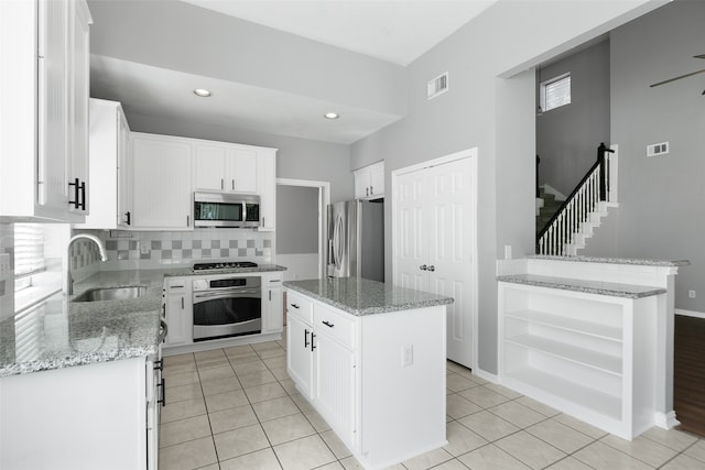 kitchen with a center island, backsplash, white cabinets, sink, and stainless steel appliances