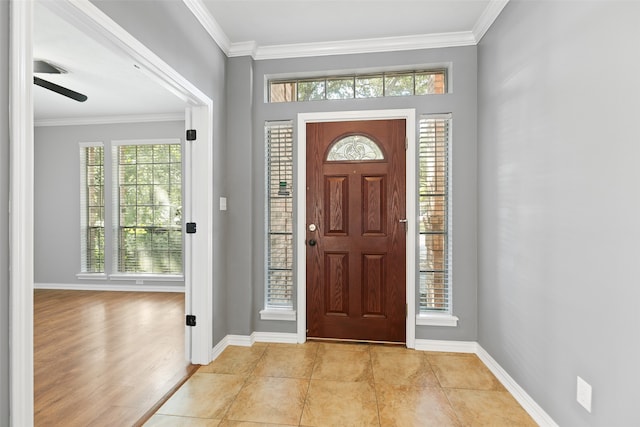 tiled foyer entrance featuring ceiling fan and crown molding