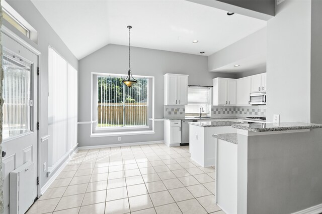 kitchen featuring decorative backsplash, stainless steel appliances, vaulted ceiling, and white cabinetry