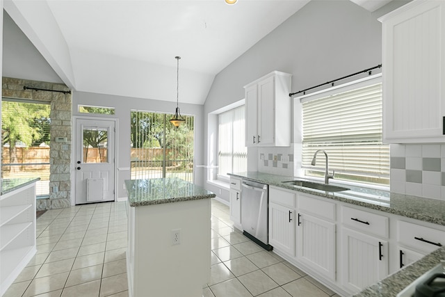 kitchen with white cabinets, sink, vaulted ceiling, stainless steel dishwasher, and decorative backsplash