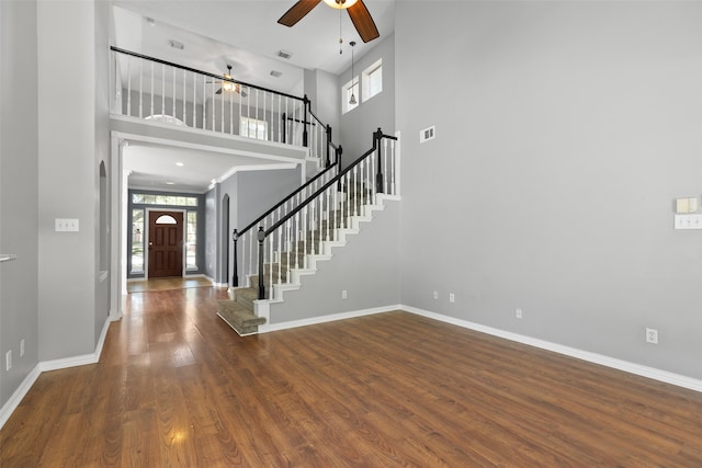 foyer with ceiling fan, wood-type flooring, and a towering ceiling