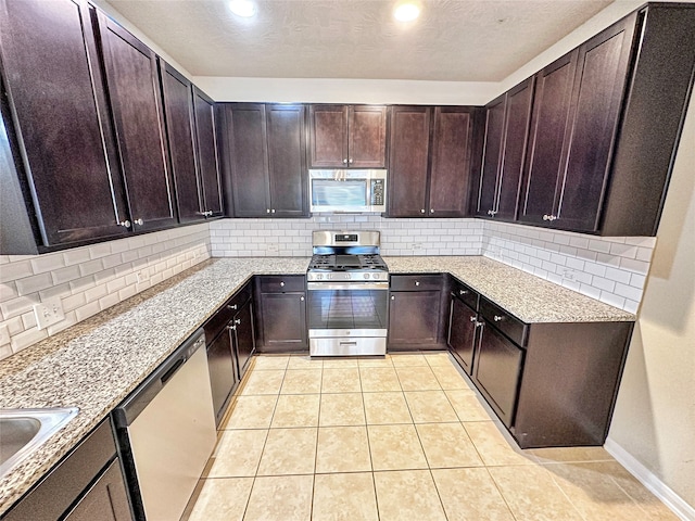 kitchen featuring decorative backsplash, dark brown cabinets, light stone counters, light tile patterned flooring, and stainless steel appliances