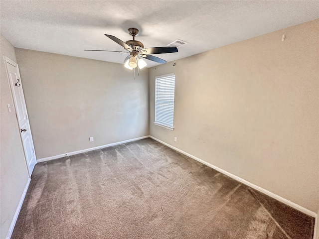 spare room with a textured ceiling, ceiling fan, and dark colored carpet