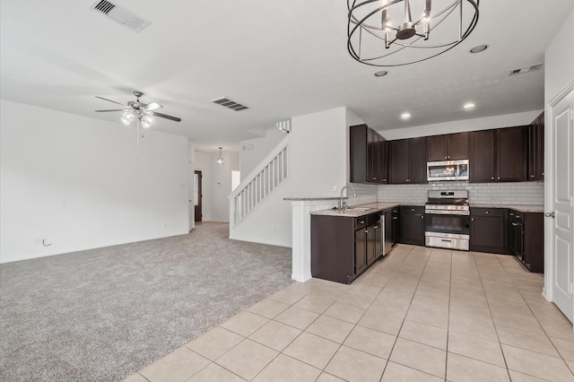 10 Garden Ridge Ct, Manvel, TX 77578 - kitchen featuring stainless steel appliances, a sink, open floor plan, dark brown cabinets, and light carpet