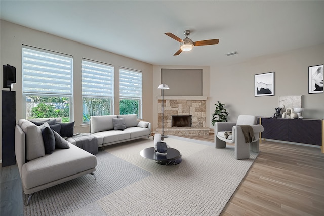 living room with light hardwood / wood-style floors, a fireplace, and ceiling fan