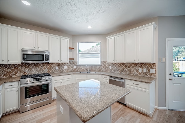 kitchen featuring a center island, stainless steel appliances, light hardwood / wood-style floors, and white cabinetry