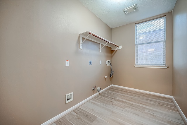 laundry area featuring hookup for an electric dryer, light wood-type flooring, hookup for a gas dryer, a textured ceiling, and washer hookup