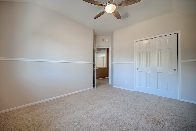 unfurnished bedroom featuring a closet, ceiling fan, vaulted ceiling, and light colored carpet