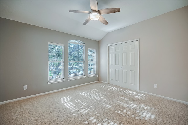 unfurnished bedroom with a closet, ceiling fan, lofted ceiling, and light colored carpet