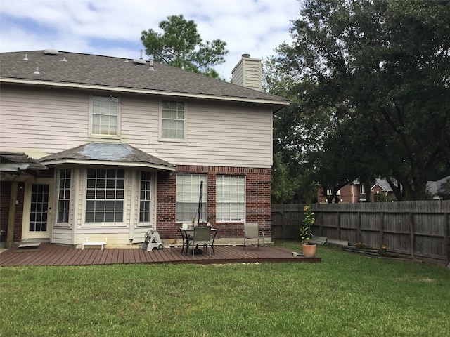 rear view of property featuring a chimney, a wooden deck, roof with shingles, and brick siding