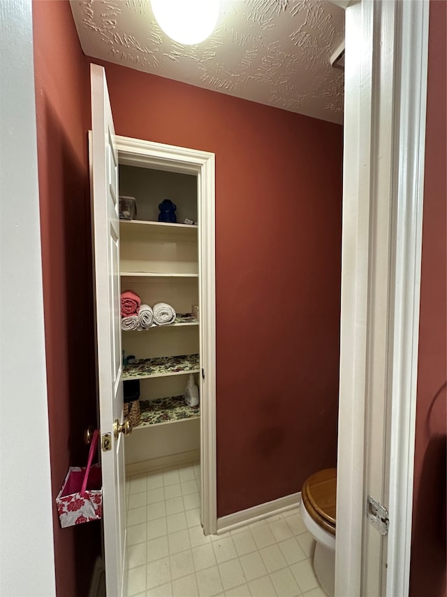 bathroom with toilet, a textured ceiling, and tile patterned flooring