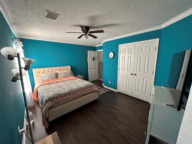 bedroom featuring a closet, dark wood-type flooring, crown molding, a textured ceiling, and ceiling fan