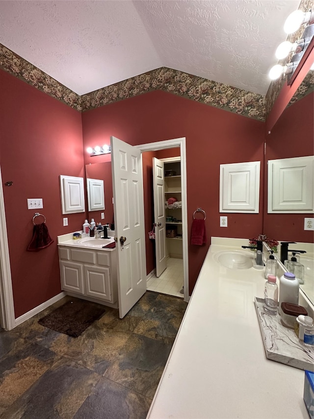 bathroom with vanity, a textured ceiling, and lofted ceiling