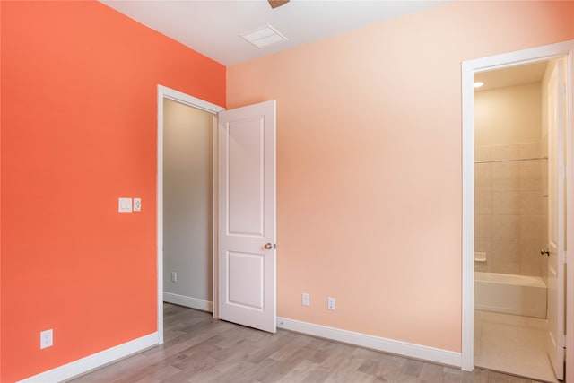 unfurnished bedroom featuring light wood-type flooring and ensuite bath