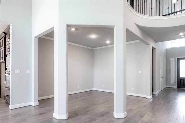 foyer entrance with light hardwood / wood-style floors, crown molding, and a towering ceiling