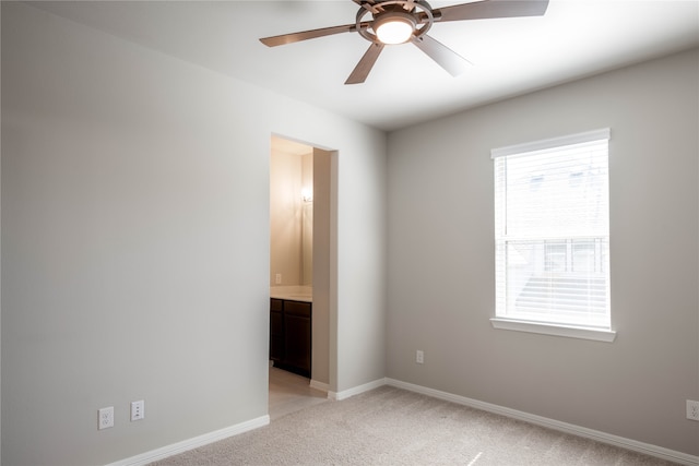 unfurnished bedroom with ensuite bathroom, light colored carpet, and ceiling fan