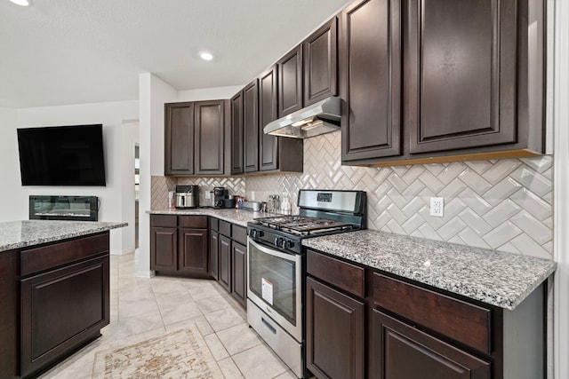 kitchen with dark brown cabinetry, light stone counters, light tile patterned floors, stainless steel gas stove, and decorative backsplash