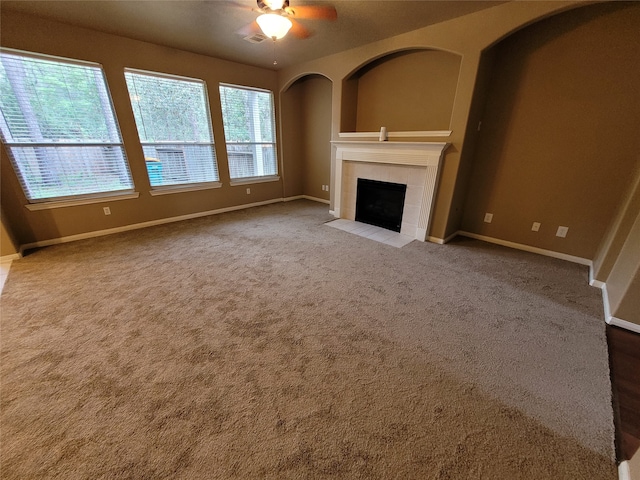 unfurnished living room with a fireplace, ceiling fan, and carpet