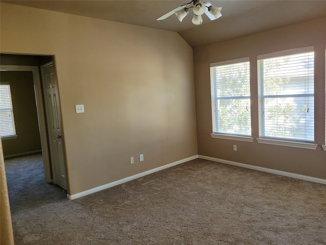 carpeted spare room featuring ceiling fan, vaulted ceiling, and a healthy amount of sunlight