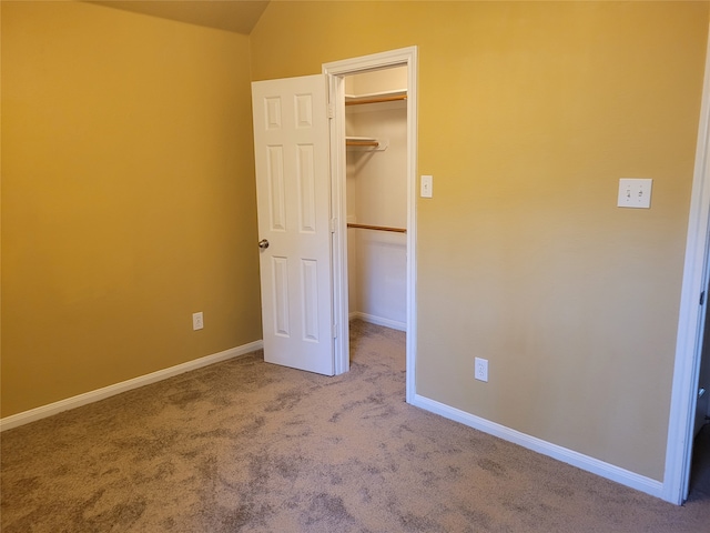 unfurnished bedroom featuring a spacious closet, a closet, vaulted ceiling, and carpet