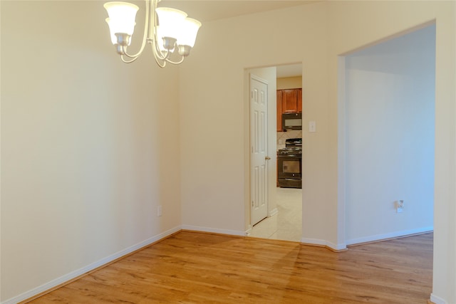 spare room with light hardwood / wood-style flooring and a chandelier