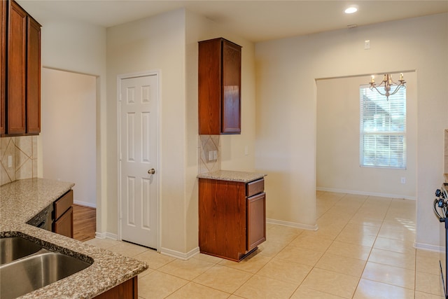 kitchen featuring tasteful backsplash, light stone countertops, hanging light fixtures, light tile patterned floors, and an inviting chandelier