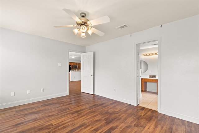 unfurnished bedroom featuring ceiling fan, dark hardwood / wood-style flooring, and ensuite bath