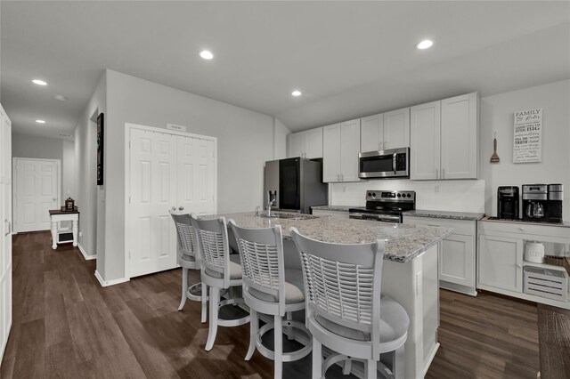 kitchen featuring white cabinetry, dark hardwood / wood-style floors, appliances with stainless steel finishes, and a kitchen island with sink