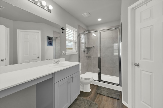 bathroom with a shower with door, hardwood / wood-style floors, vanity, and toilet