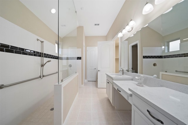 bathroom featuring vaulted ceiling, tiled shower, vanity, and tile patterned flooring