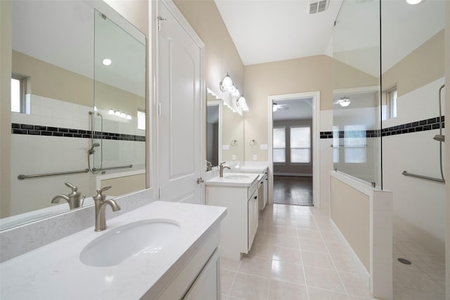 bathroom featuring ceiling fan, a tile shower, vanity, vaulted ceiling, and tile patterned floors