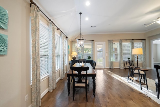 dining space with crown molding, lofted ceiling, dark wood-type flooring, and a notable chandelier