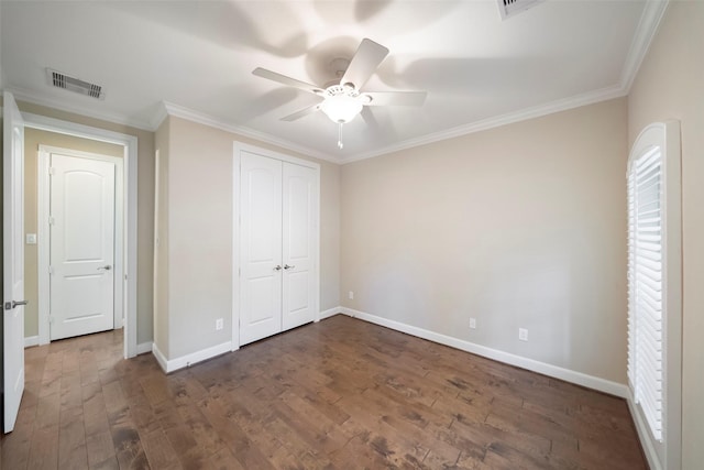 unfurnished bedroom featuring crown molding, ceiling fan, dark hardwood / wood-style flooring, and a closet