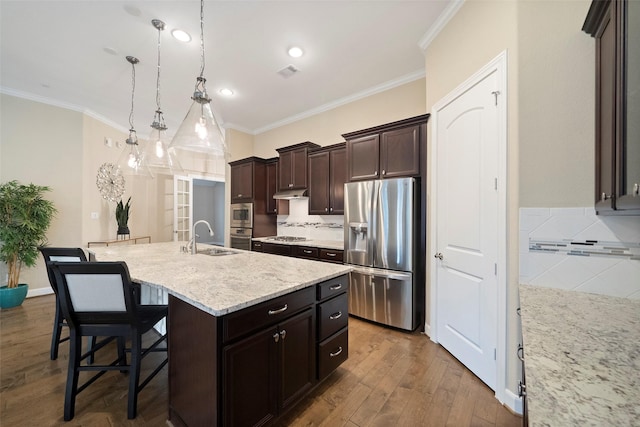 kitchen featuring sink, appliances with stainless steel finishes, a kitchen island with sink, hardwood / wood-style floors, and hanging light fixtures