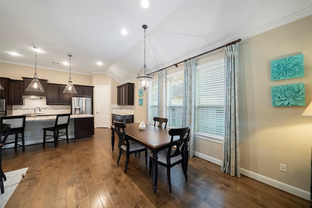 dining space featuring sink, crown molding, dark wood-type flooring, and vaulted ceiling