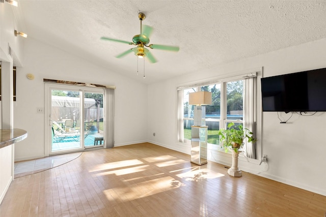 unfurnished living room with ceiling fan, vaulted ceiling, light hardwood / wood-style floors, and a healthy amount of sunlight