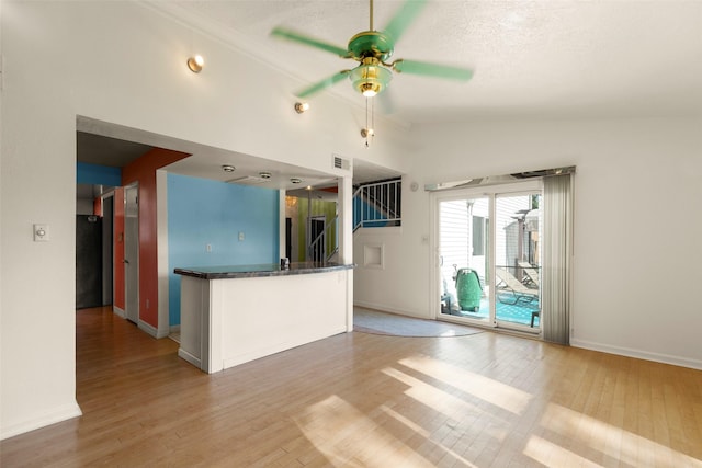 kitchen featuring ceiling fan, lofted ceiling, a textured ceiling, and light wood-type flooring