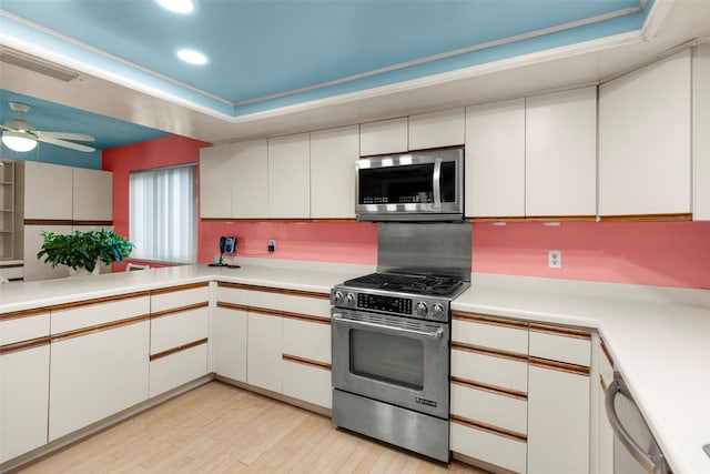 kitchen with white cabinetry, tasteful backsplash, appliances with stainless steel finishes, ceiling fan, and light hardwood / wood-style floors