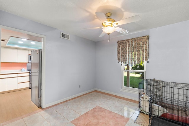 interior space with light tile patterned floors, a textured ceiling, and ceiling fan