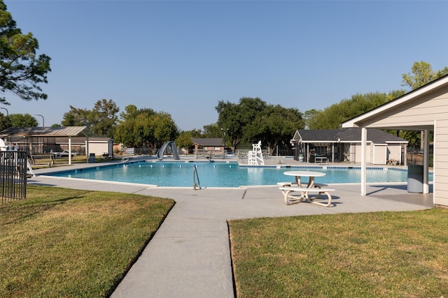 view of pool featuring a yard, a patio, and a water slide