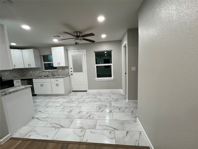 kitchen featuring light stone counters, white cabinets, ceiling fan, sink, and decorative backsplash