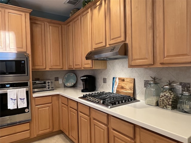 kitchen with light tile patterned floors, stainless steel appliances, and tasteful backsplash